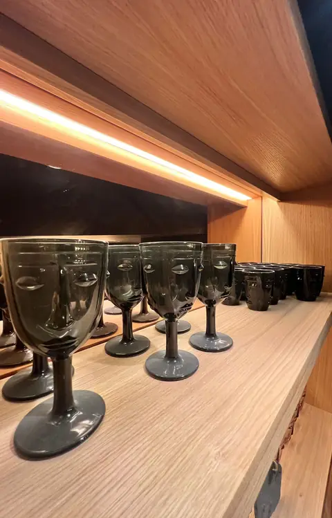 Comptoir en bois clair sous un bandeau éclairé, avec des verres fumés alignés.