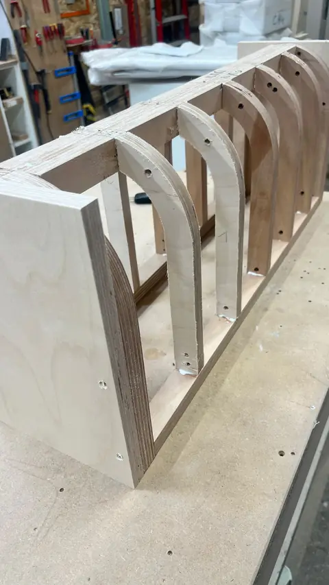 Structure en bois composée d'arches découpées, en cours d'assemblage.
