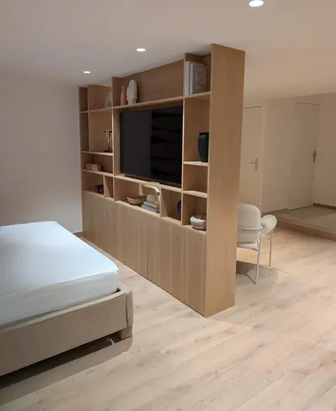 Bibliothèque double face en chêne séparant une chambre, avec emplacement TV.