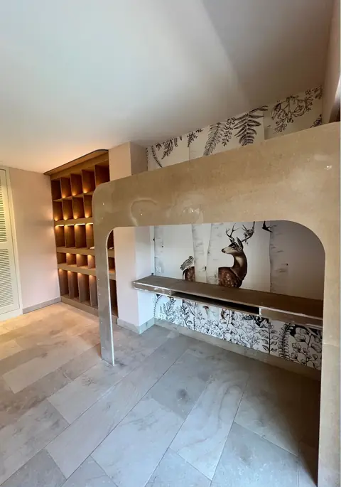 Grande niche en arche avec plateau en bois, et bibliothèque éclairée en arrière-plan.