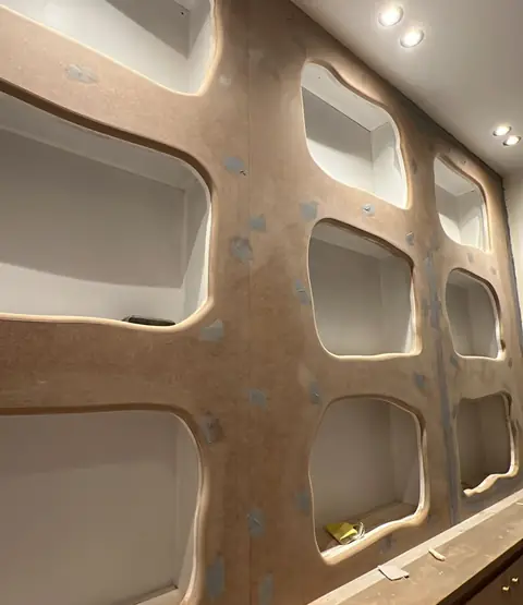 Meuble mural à niches aux formes arrondies, avec éclairage en partie basse.
