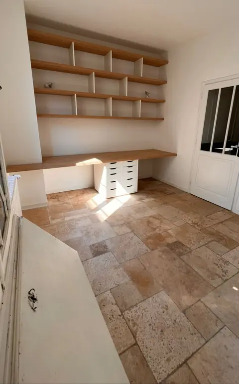 Plan de bureau et étagères en bois fixés au mur d'une pièce lumineuse.