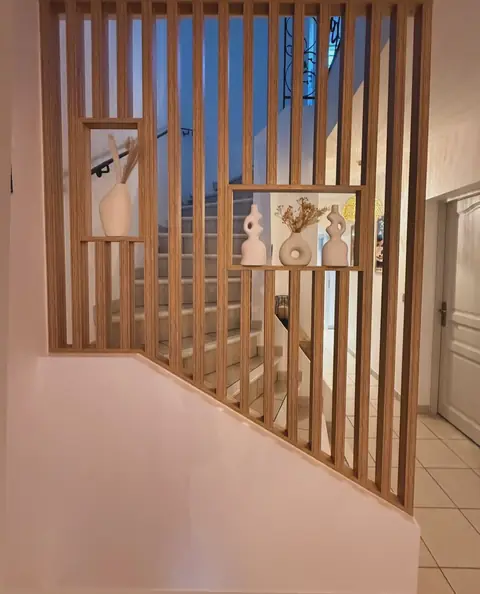 Claustra en lames de bois clair fermant une cage d'escalier.