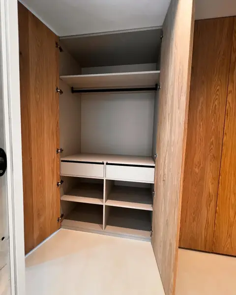 Intérieur de placard en bois avec penderie, tiroirs et étagères basses.