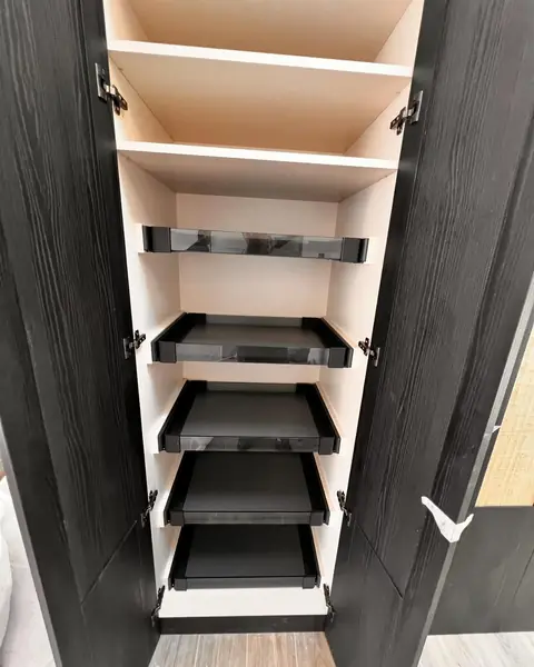 Plateaux coulissants noirs superposés à l'intérieur d'un dressing.