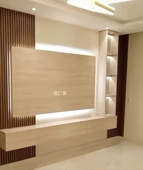 Mur habillé de bois clair avec meuble TV suspendu et niches éclairées.
