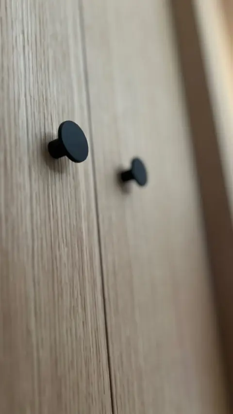 Façades en bois clair avec boutons ronds noirs.