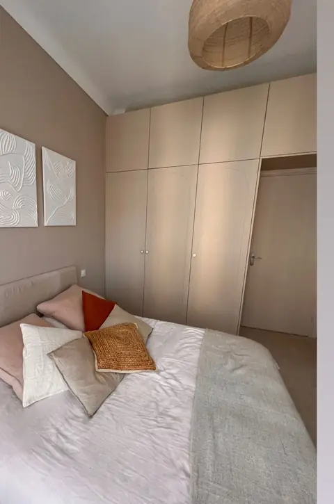 Placards beiges toute hauteur dans une chambre, intégrés au mur derrière le lit.