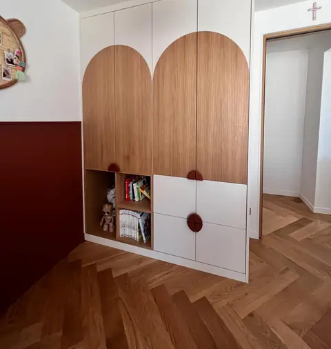 Placards de chambre d'enfant à portes en arche en bois, avec niches et tiroirs blancs.