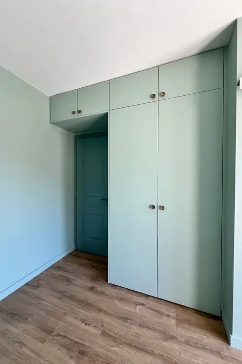 Placards vert pâle installés sous un plafond en pente, autour d'une porte.