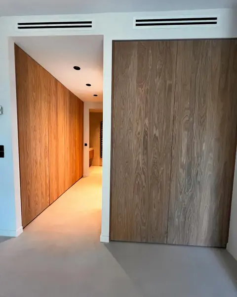 Grandes portes en bois toute hauteur dans un couloir lumineux.