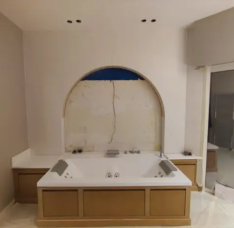 Baignoire habillée de bois sous une niche en arche.