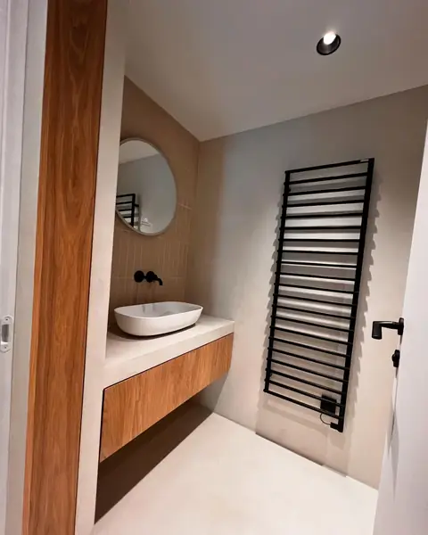 Meuble vasque suspendu en bois avec vasque blanche et miroir rond.