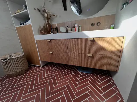 Meuble vasque en bois cannelé au-dessus d'un sol à chevrons en terre cuite.