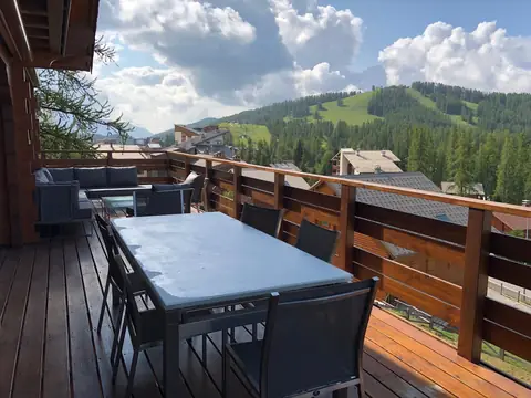 Terrasse en bois du chalet, face aux pistes et aux forêts de Valberg.